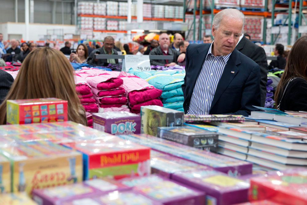 Joe Biden looking over a display of children's books inside a Costco.  The commission suggests opening voting locations at places where people frequently run errands, like Costco and Walmart.  
