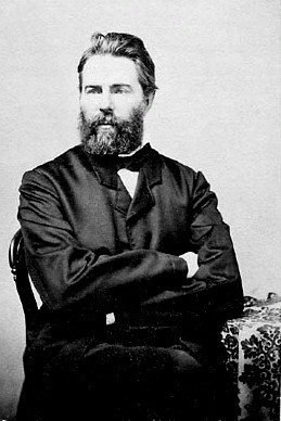 A portrait of Herman Melville from 1860.  He has longish hair for the era, and full beard, on the long side, but tidy.  He wears a black suit coat, and his arms are crossed.  